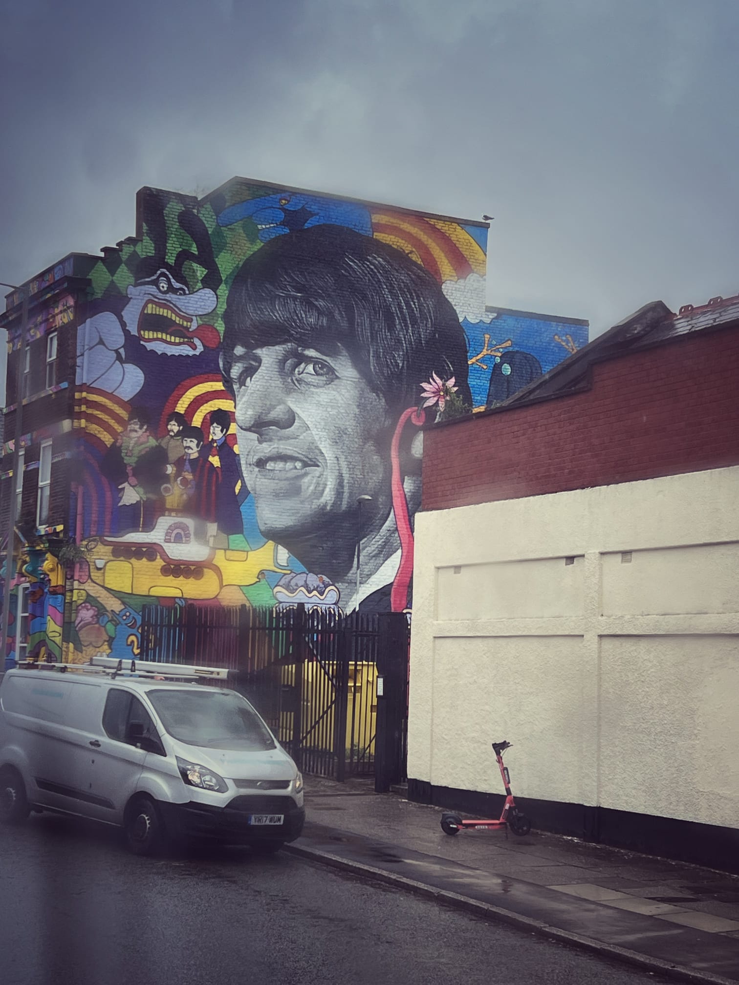 A large street mural of a Beatle beside Yellow Submarine artwork on the side of a building