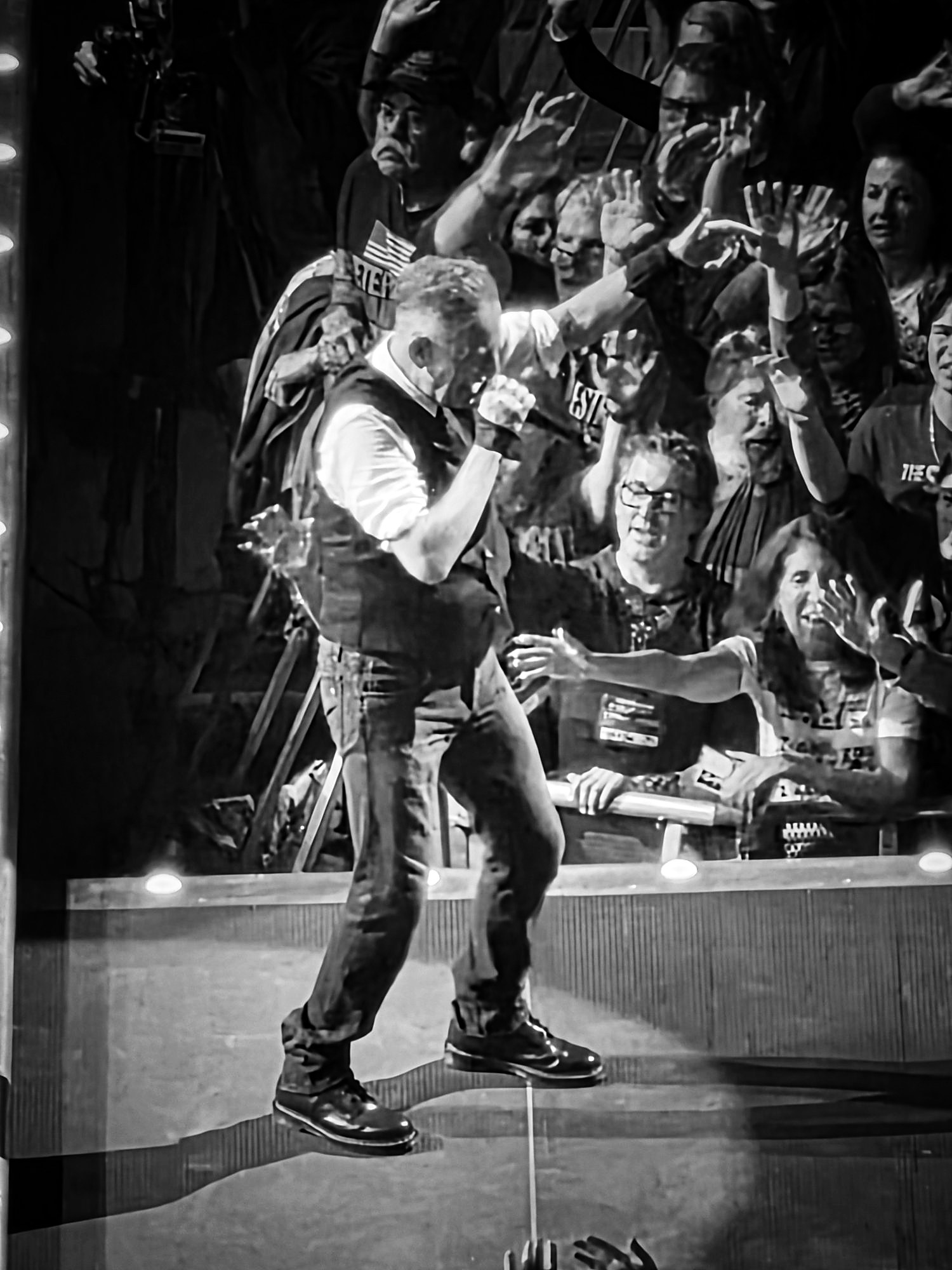 A singer performing on a catwalk stage with the crowd reaching up