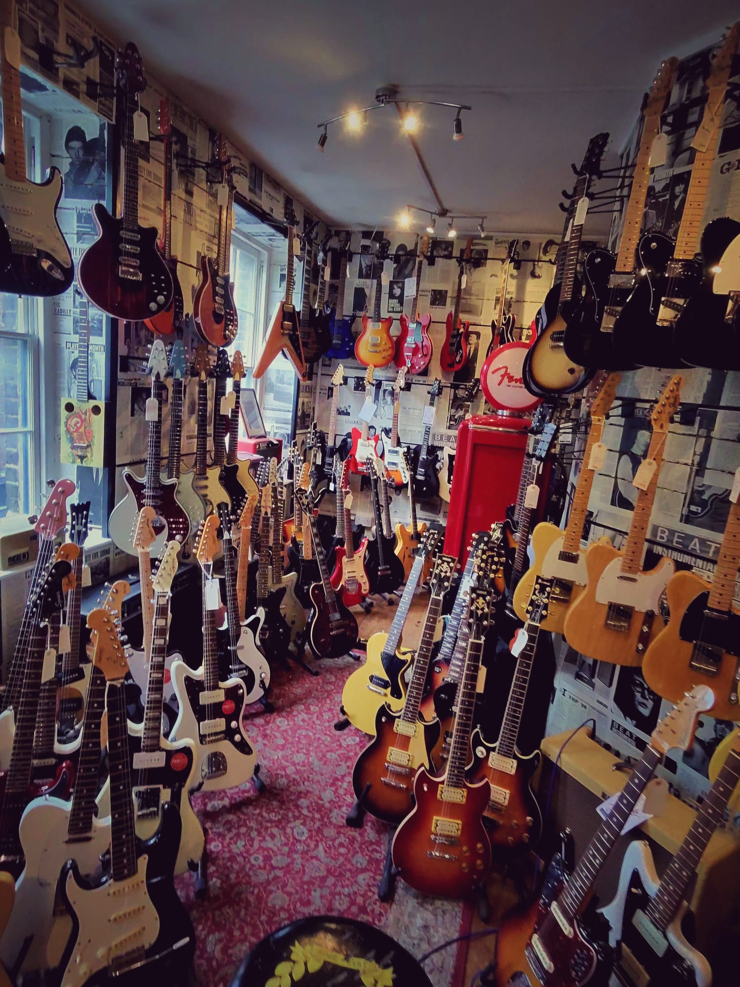 A narrow guitar shop packed floor to ceiling with electric guitars