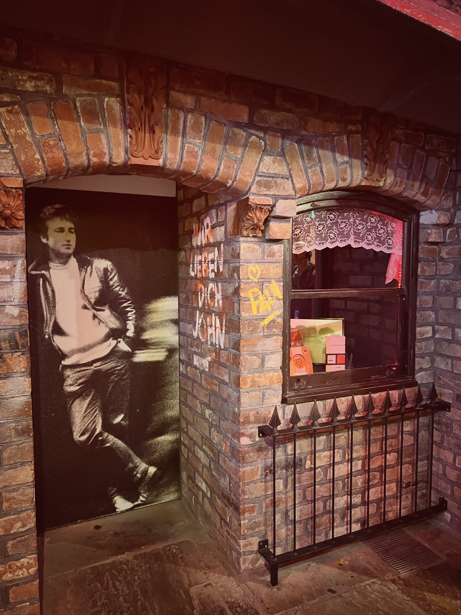 Brick cellar doorway with a large photograph of John Lennon and the words Wir lieben dich John painted on the wall